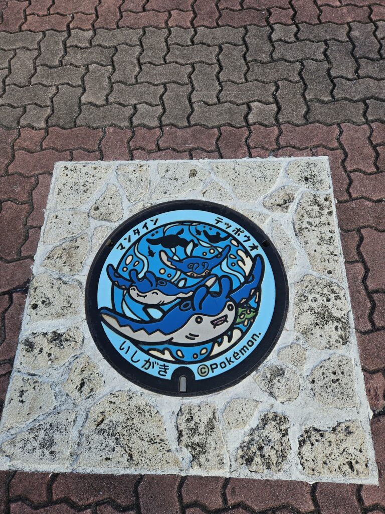Official Pokémon manhole cover in Ishigaki, Okinawa featuring Mantine and Remoraid on a colorful Poké Lid inspired by the island's famous manta rays and marine life.